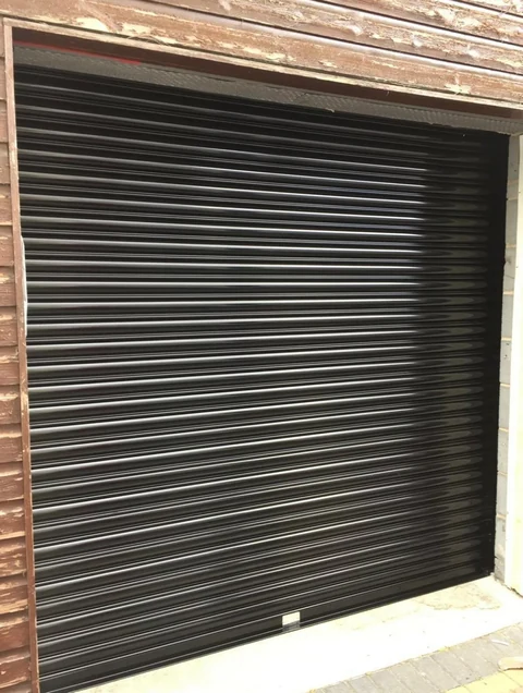 Black roller shutter fitted within a garage opening.