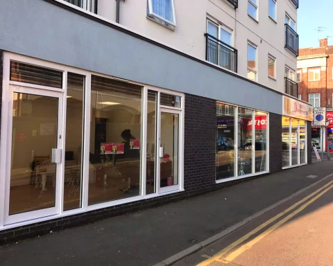 Commercial glazed frontage with white frames and multiple entrance doors.