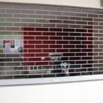 A stainless steel commercial roller grill with parallel metal bars and a crank handle.