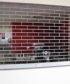 A stainless steel commercial roller grill with parallel metal bars and a crank handle.